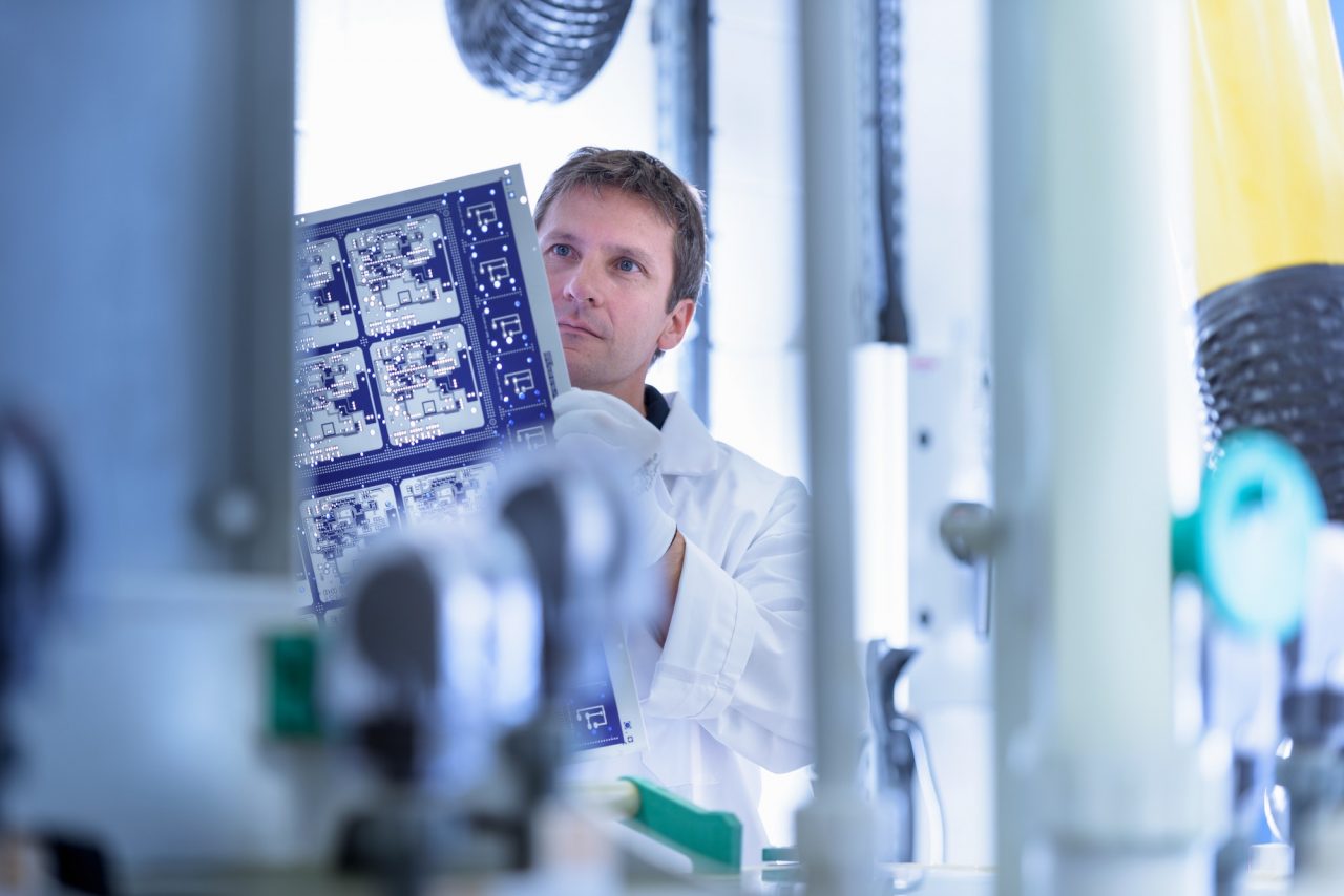 Worker inspecting circuit board by processing plant in circuit board factory